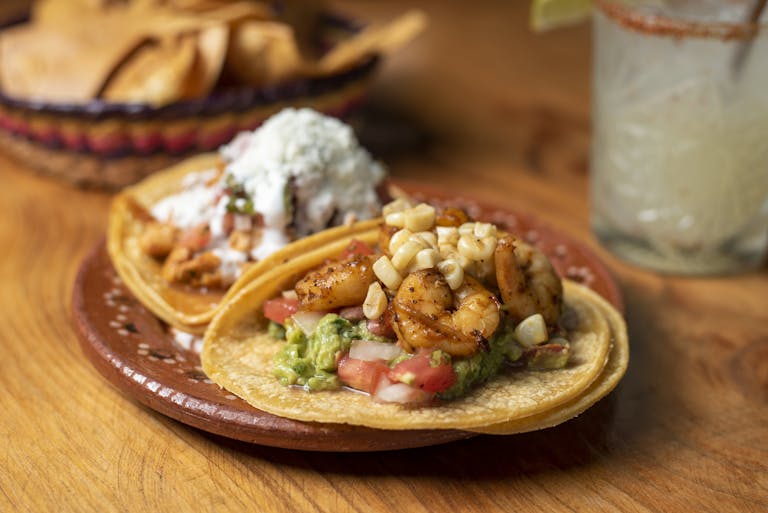 Close-up of delicious shrimp tacos with guacamole on a rustic plate. Perfect for Mexican food lovers.