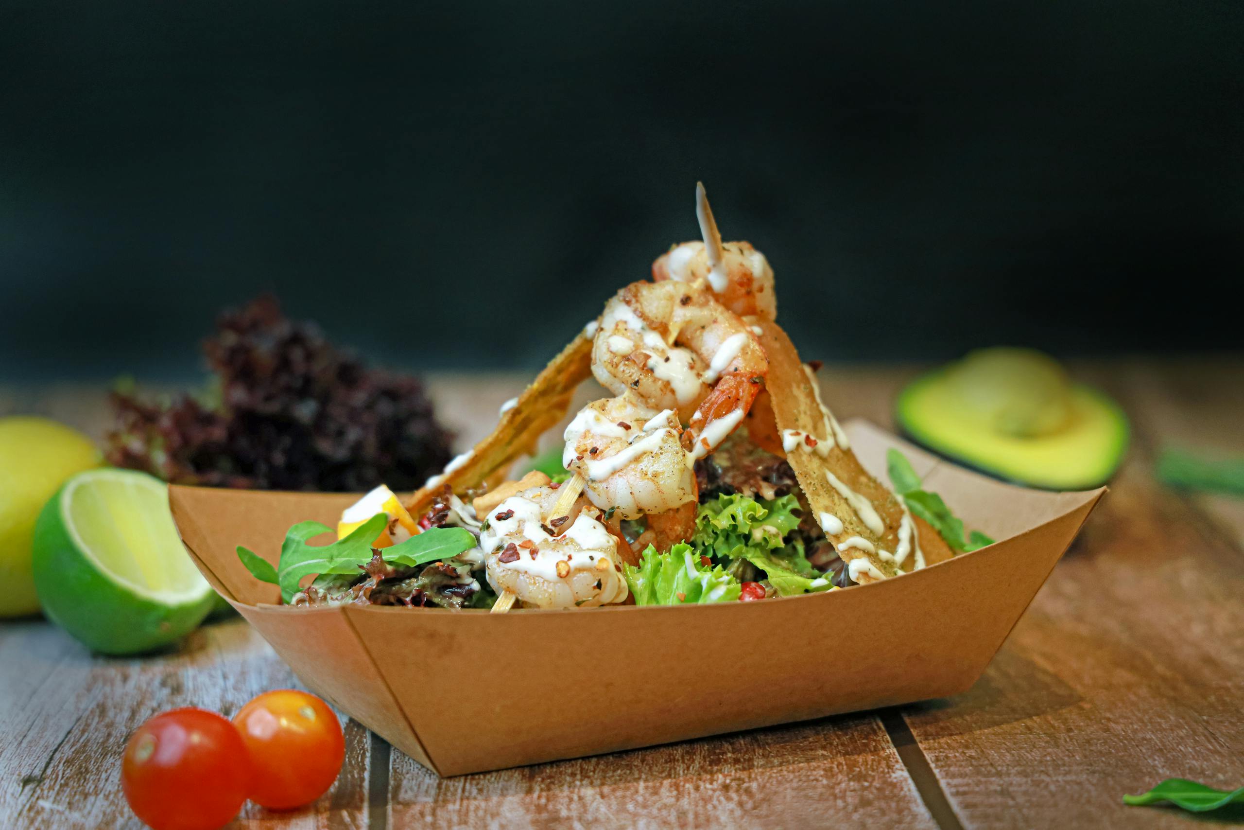 Delicious shrimp taco salad in a paper box with fresh veggies and avocado.